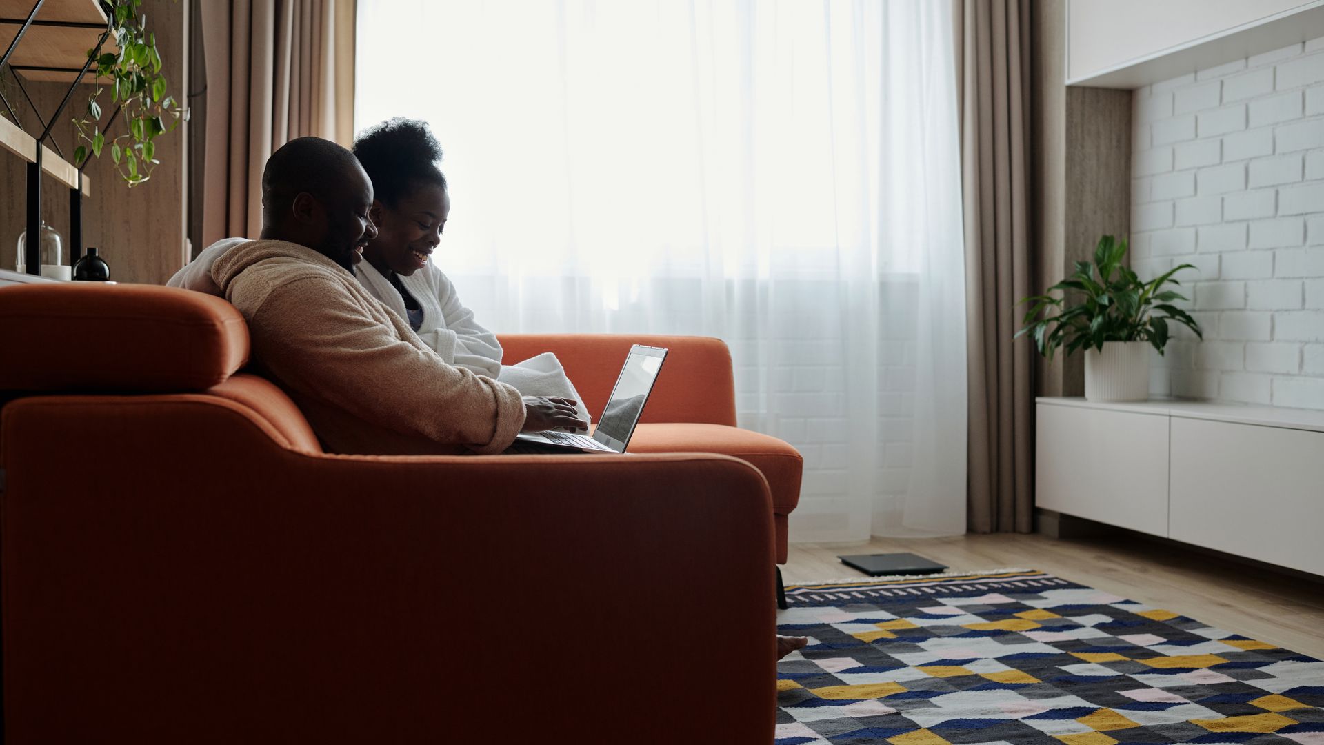 Un couple africain utilise internet sur un laptop dans son salon