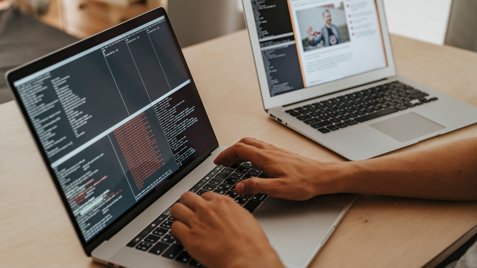 Un développeur travaille sur deux laptops avec du code à l’écran
